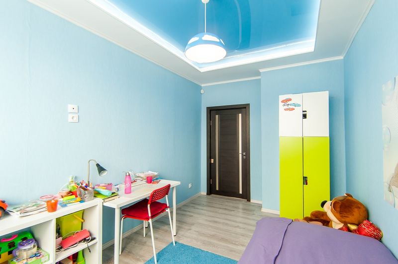Детская комната с голубыми стенами, письменным столом, кроватью и шкафом.