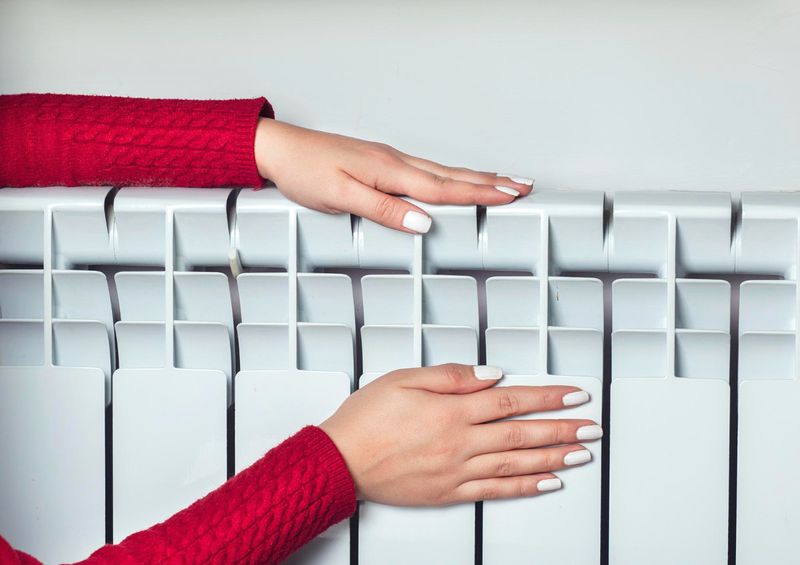 Руки на радиаторе отопления.