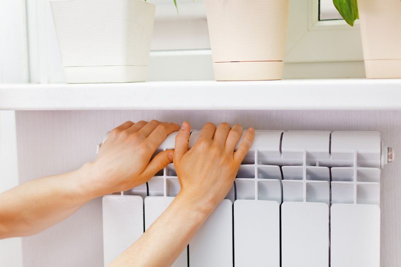 Руки на радиаторе отопления.