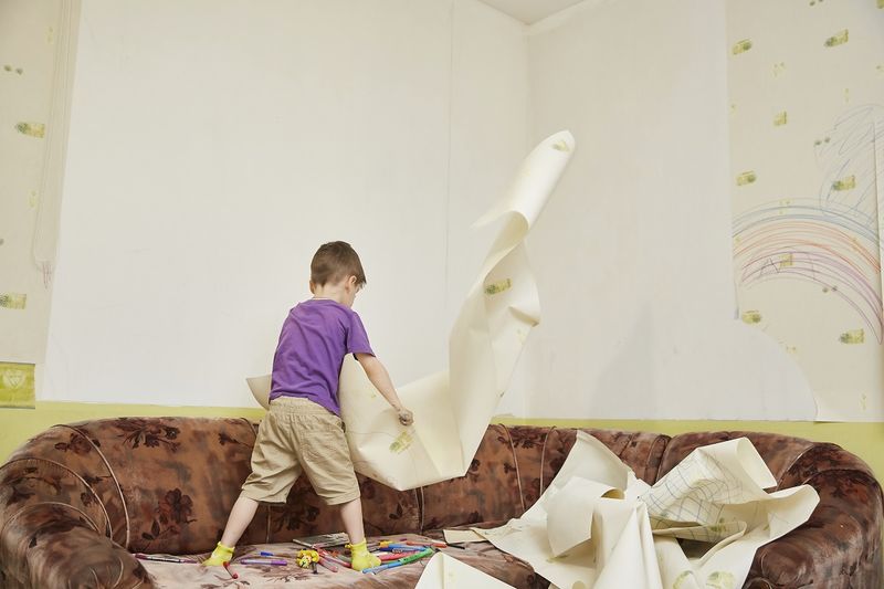 Мальчик сдирает обои.