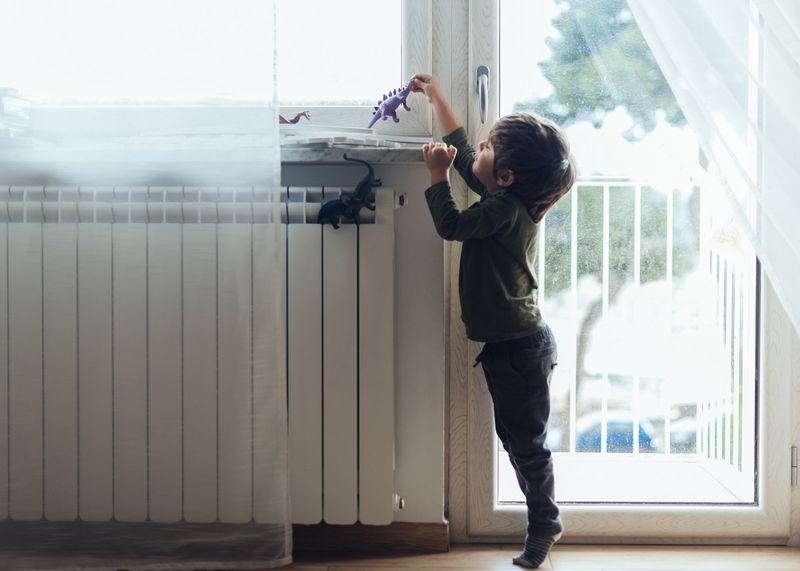 Ребенок у радиатора отопления.